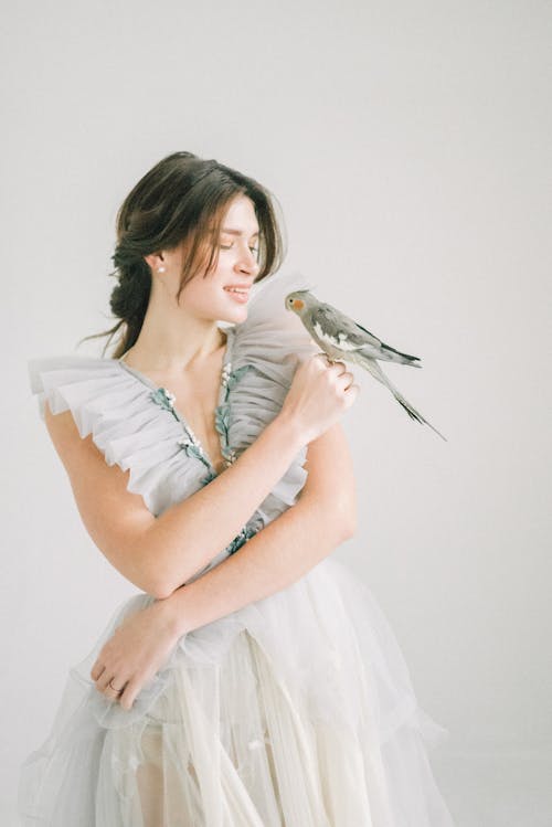 A Woman in White Dress Holding a Gray Bird