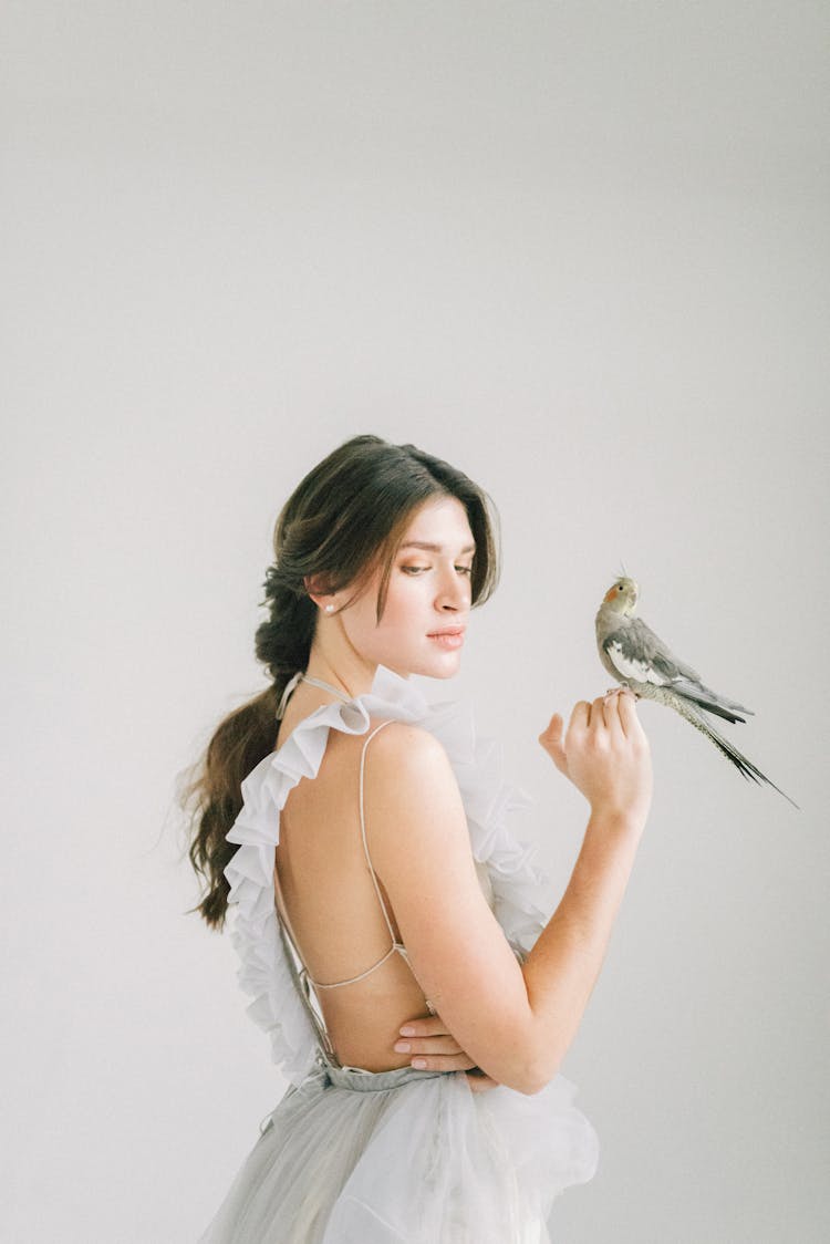 A Woman In White Dress Holding A Gray Bird