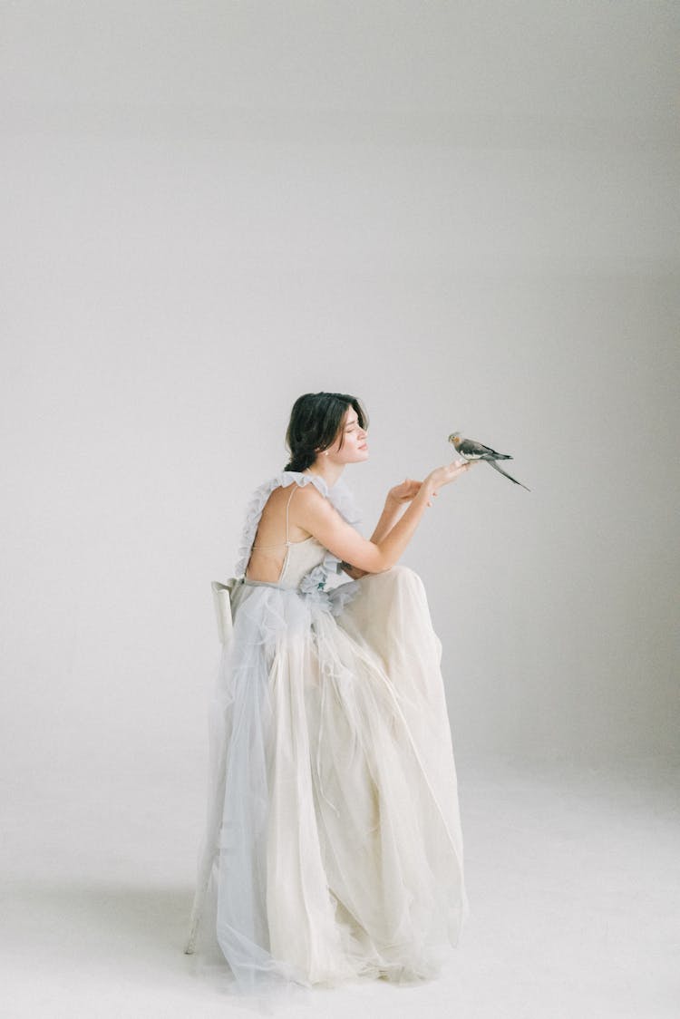 A Woman In White Dress Holding A Gray Bird