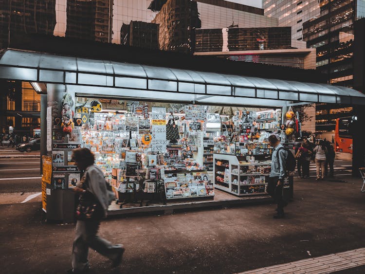 Exterior Of Modern Small Bookstore Near Busy Street At Evening