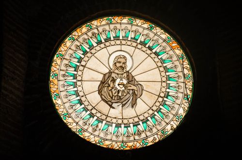 Free Circular stained glass window illustrating Jesus Christ, a serene religious artwork. Stock Photo