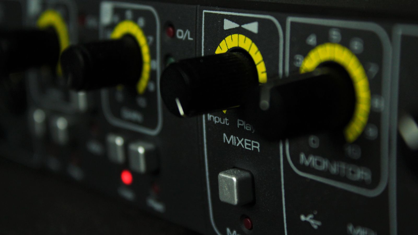 Audio mixer control panel with knobs and LED indicators in a recording studio