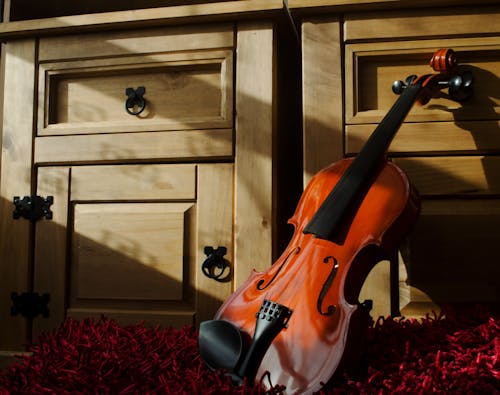 Brown Violin Leaning on Brown Wooden Cabinet