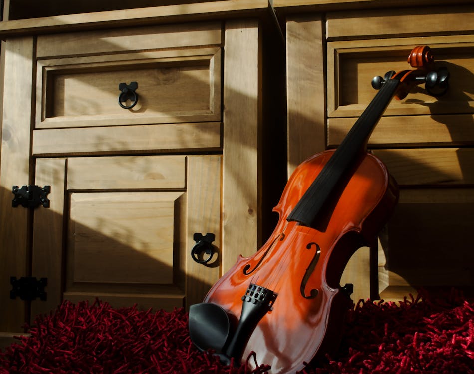 Free Brown Violin Leaning on Brown Wooden Cabinet Stock Photo