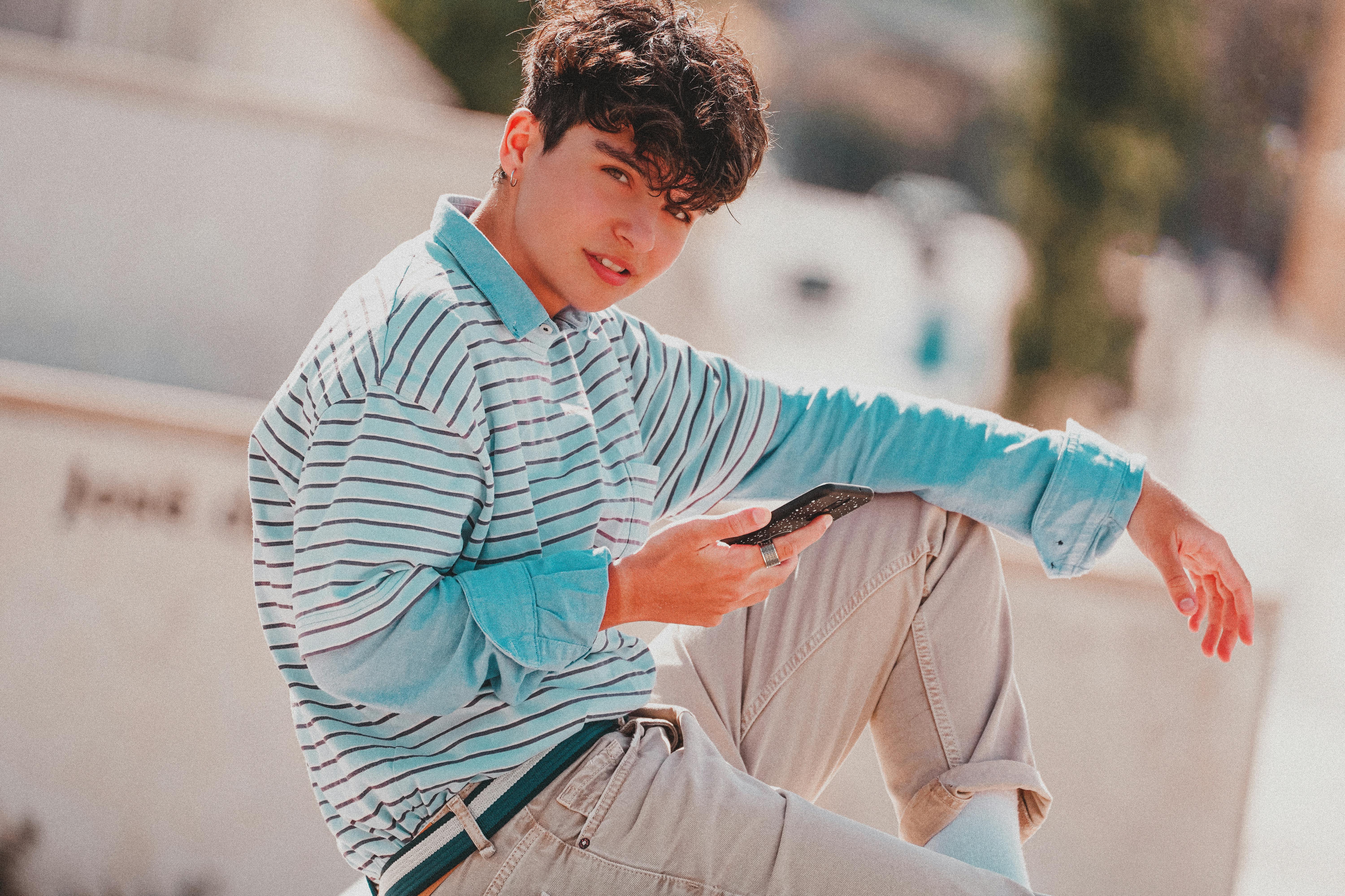 handsome teenage boy using smartphone on street