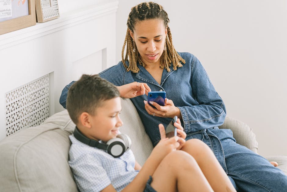 A mother and son enjoy leisure time using smartphones together indoors, sharing a joyful moment.