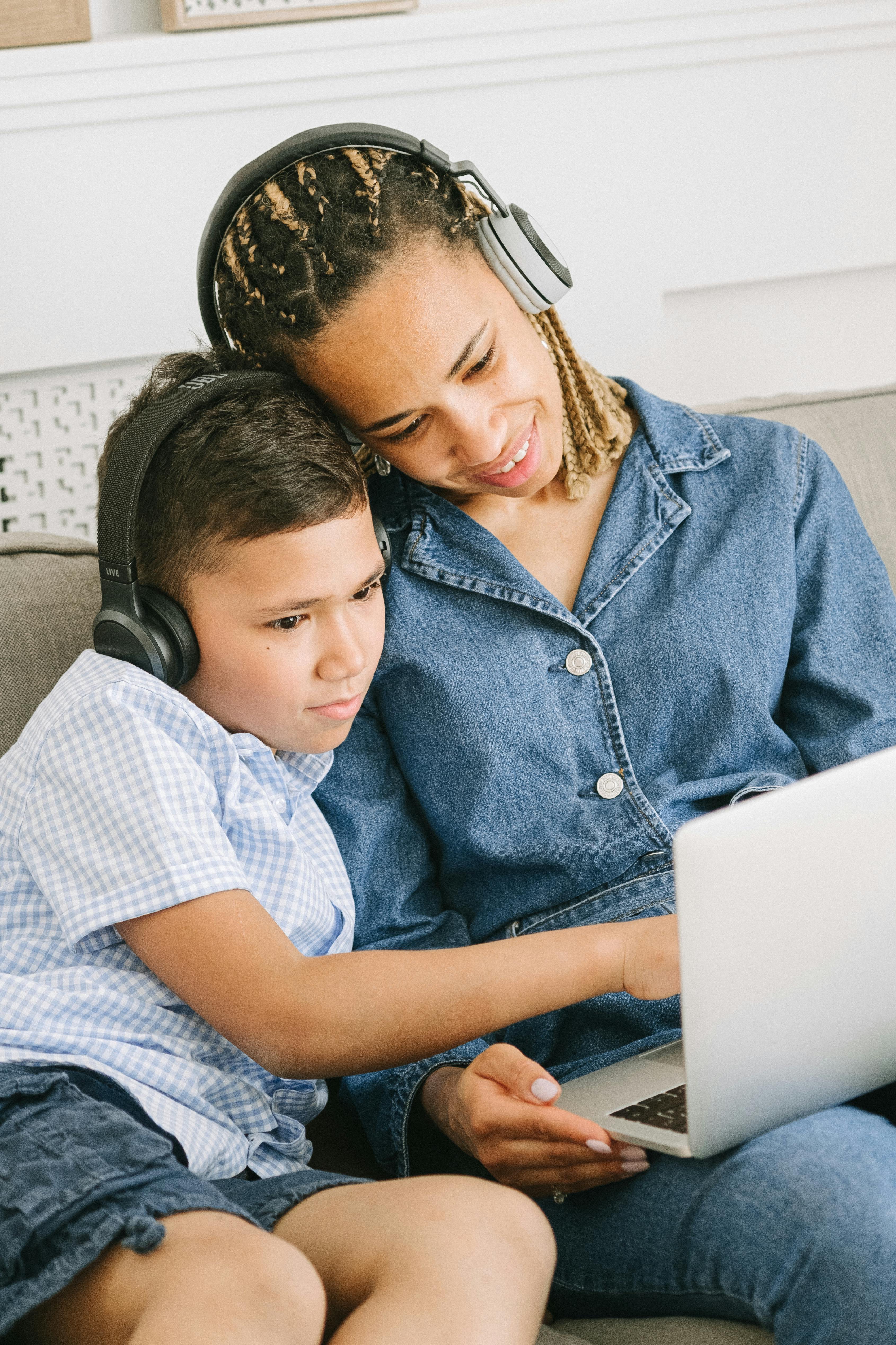 woman and boy with head phones using laptop computer