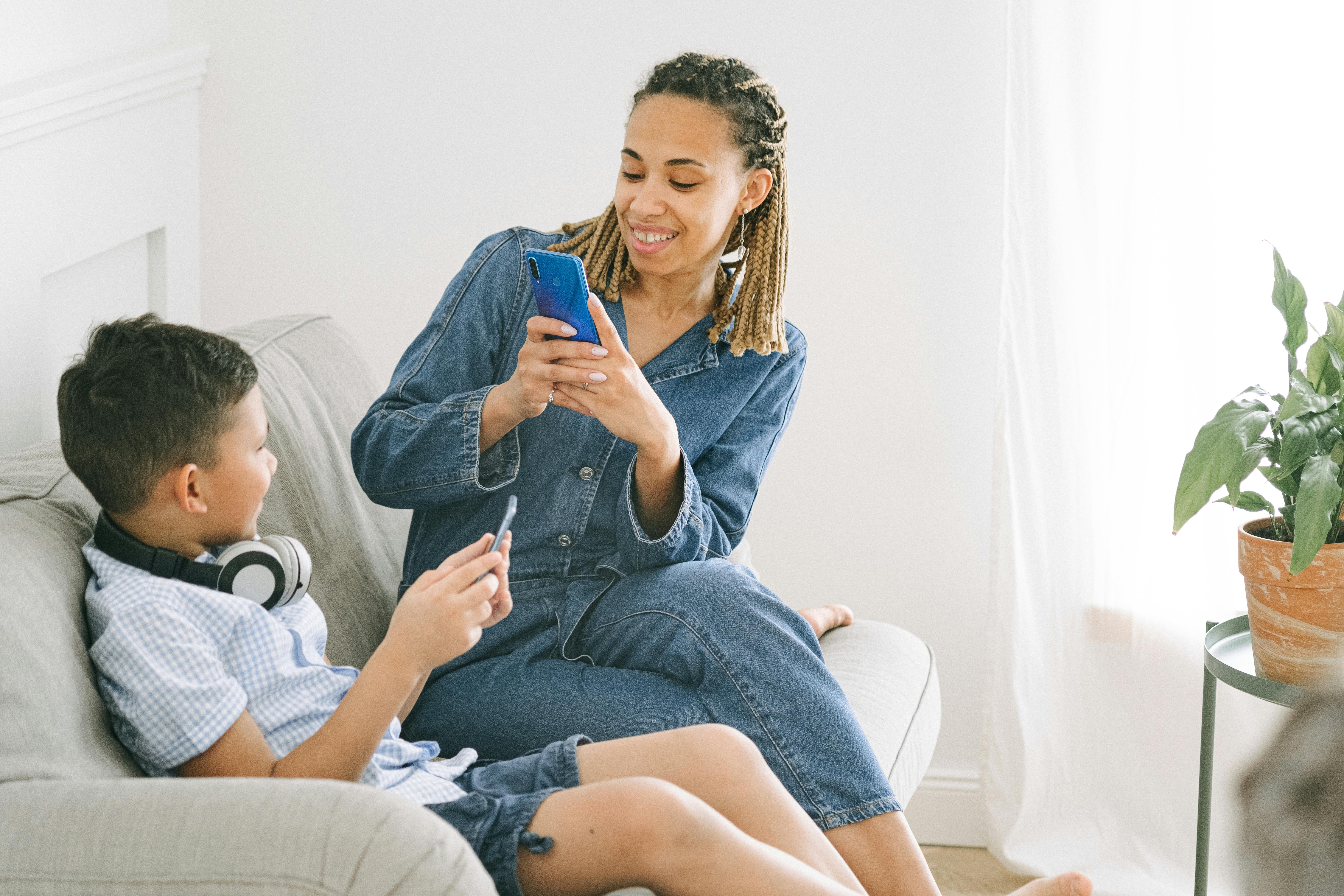 woman in blue denim jumpsuit taking photo of boy