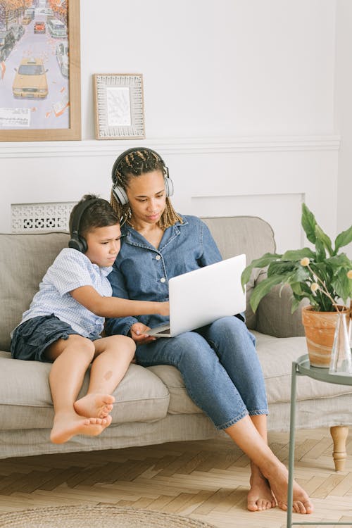 Boy and Woman Sitting on Sofa with Laptop