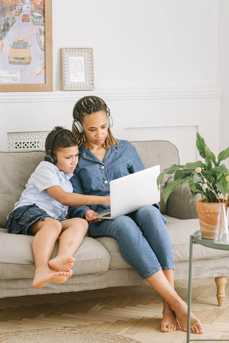 Boy And Woman Sitting On Sofa With Laptop