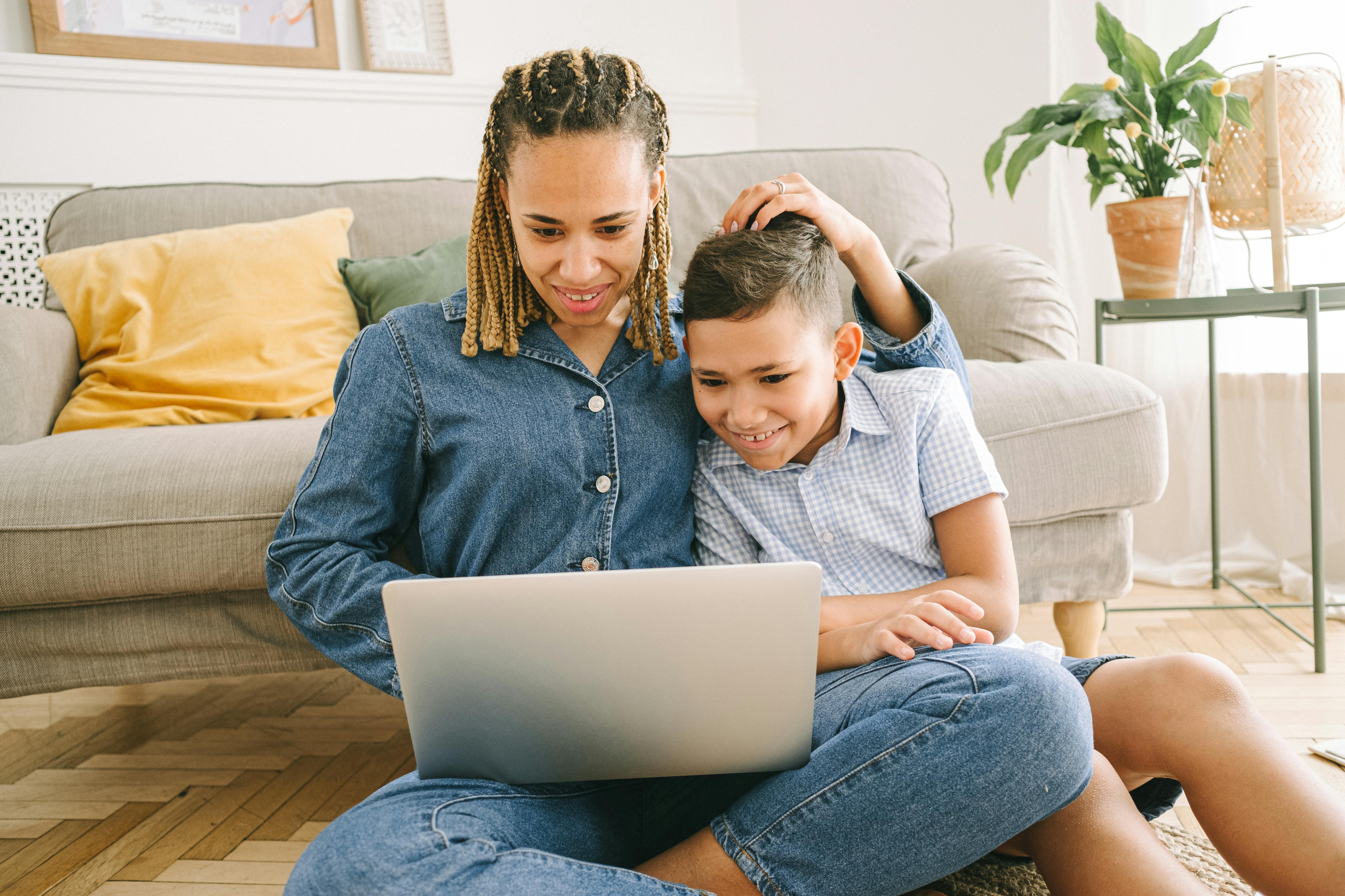 woman and young boy sitting on floor with laptop