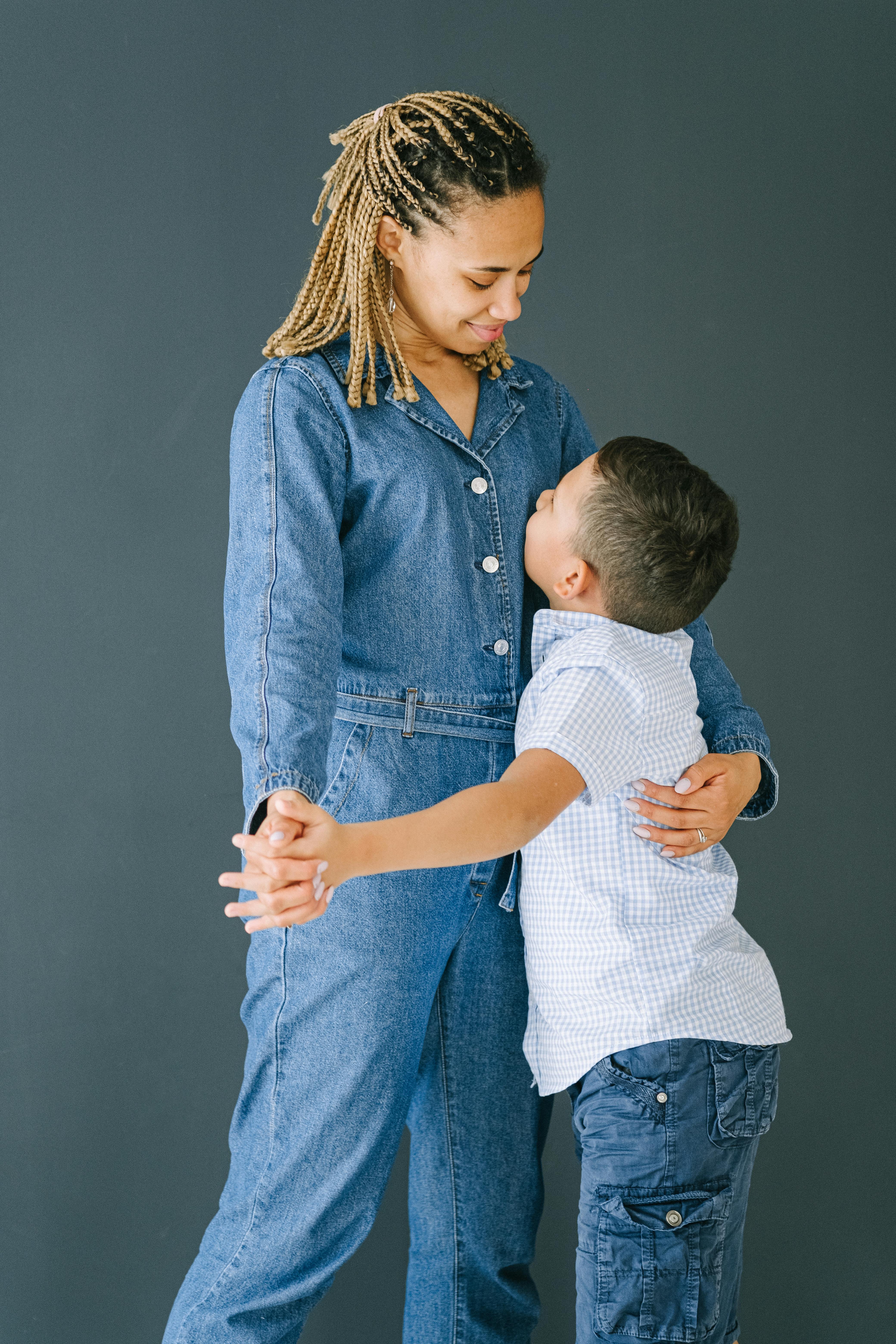 woman in denim jumpsuit hugging young boy