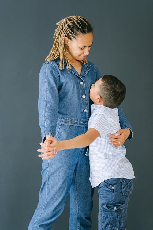 Free Woman in Denim Jumpsuit Hugging Young Boy Stock Photo