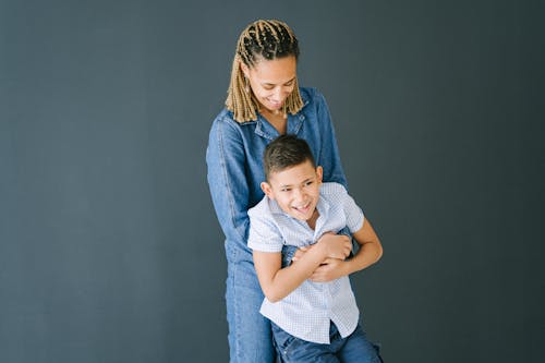 Woman in Demin Clothing Hugging Young Boy from Behind