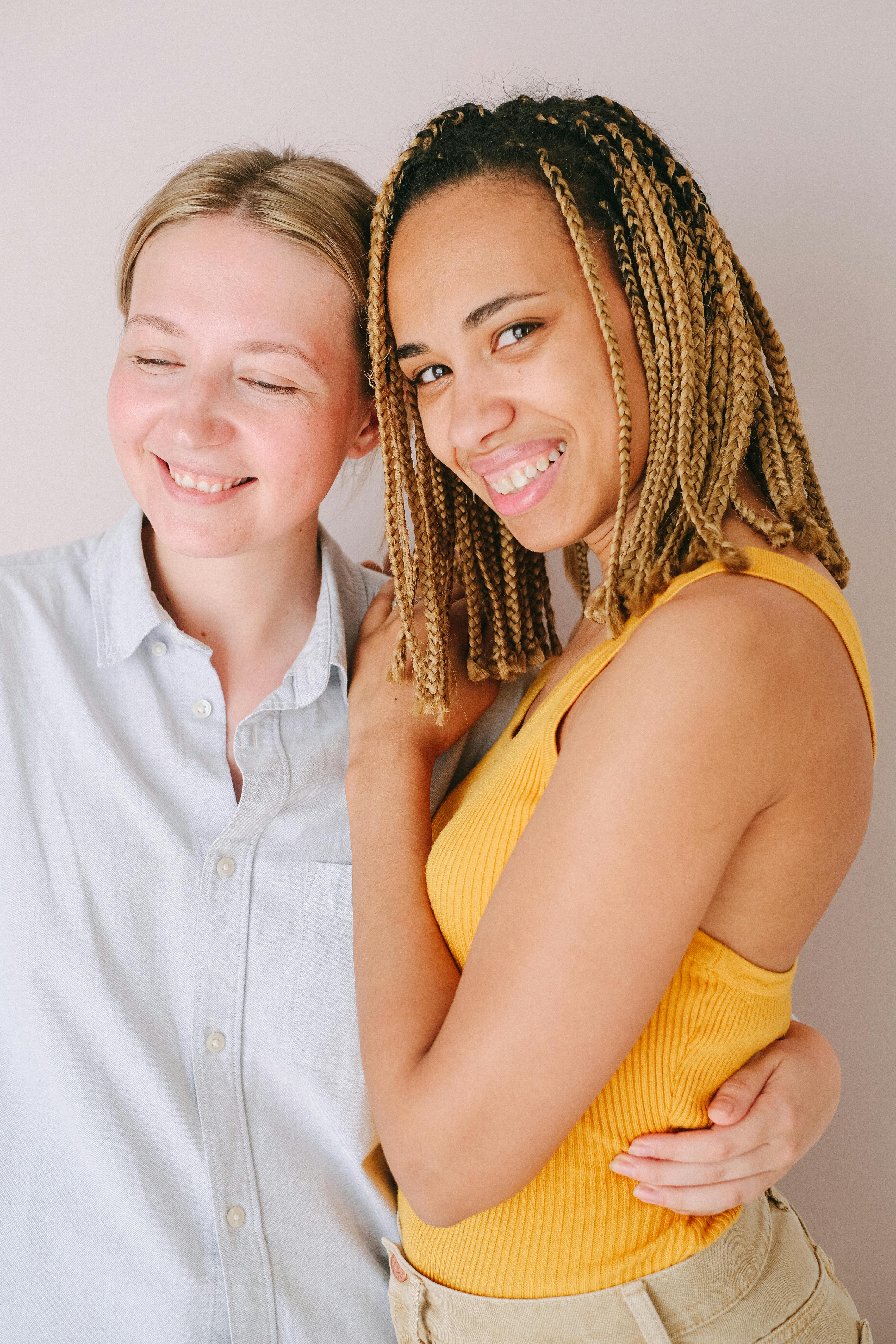 woman in yellow sleeveless top beside woman in white button up shirt