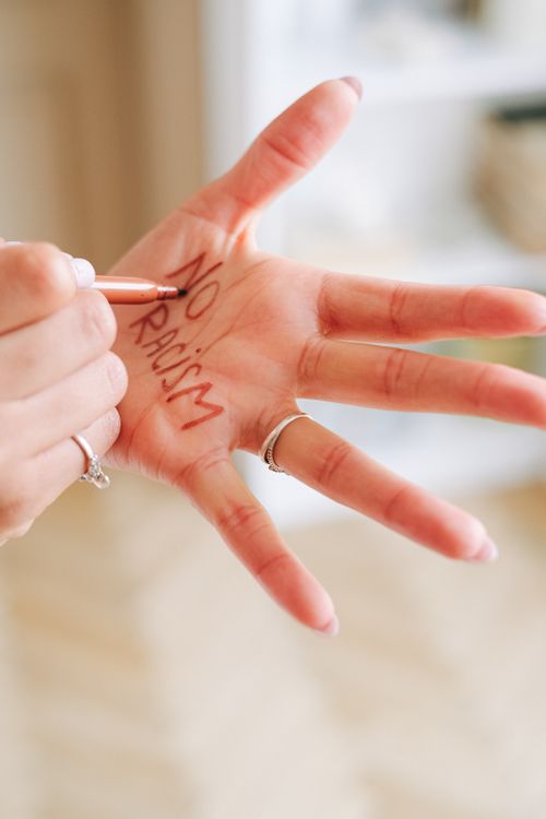 Free A close-up of a woman's hand with 'No Racism' written, promoting anti-racism. Stock Photo