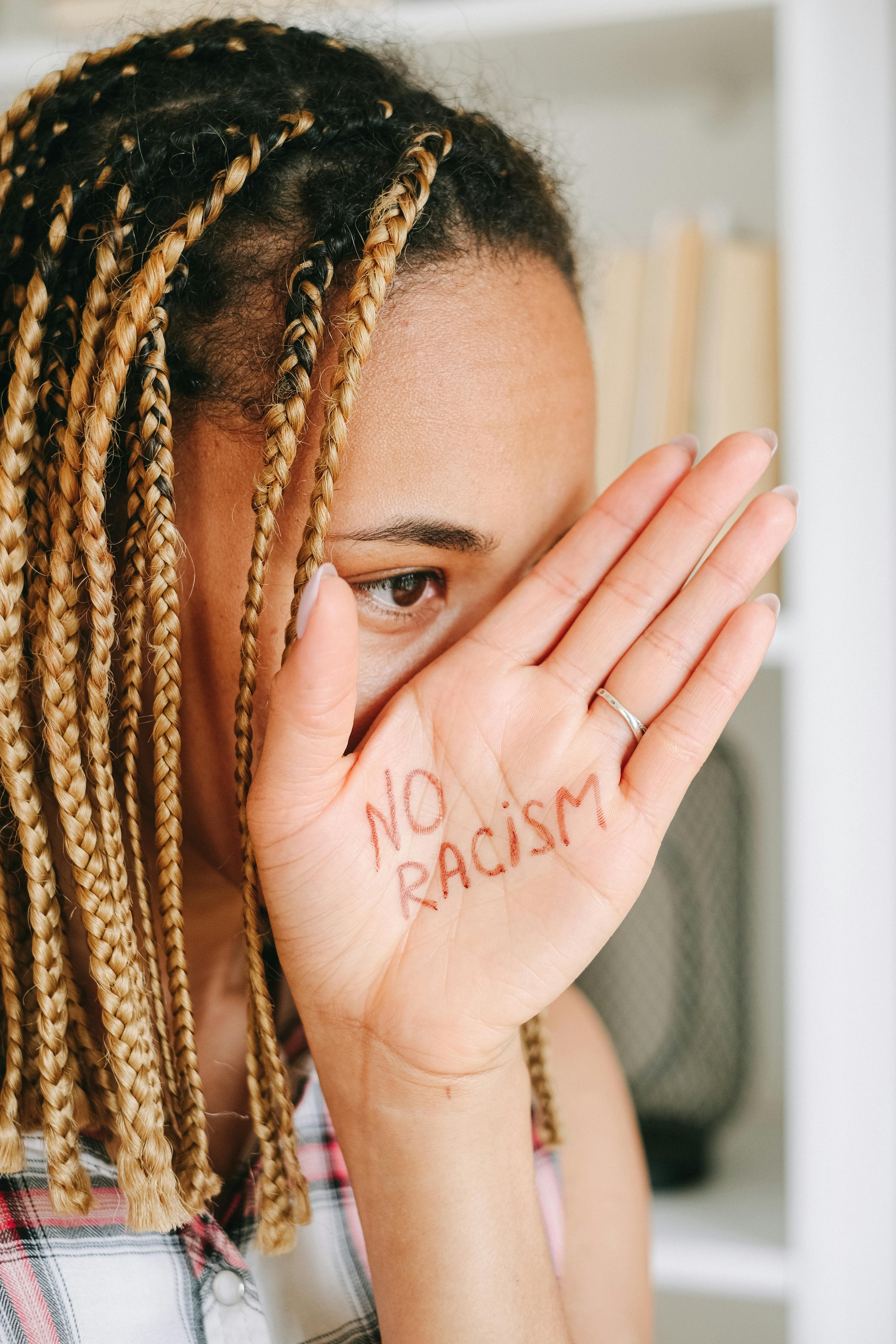 woman in white tank top covering her face with brown braided hair