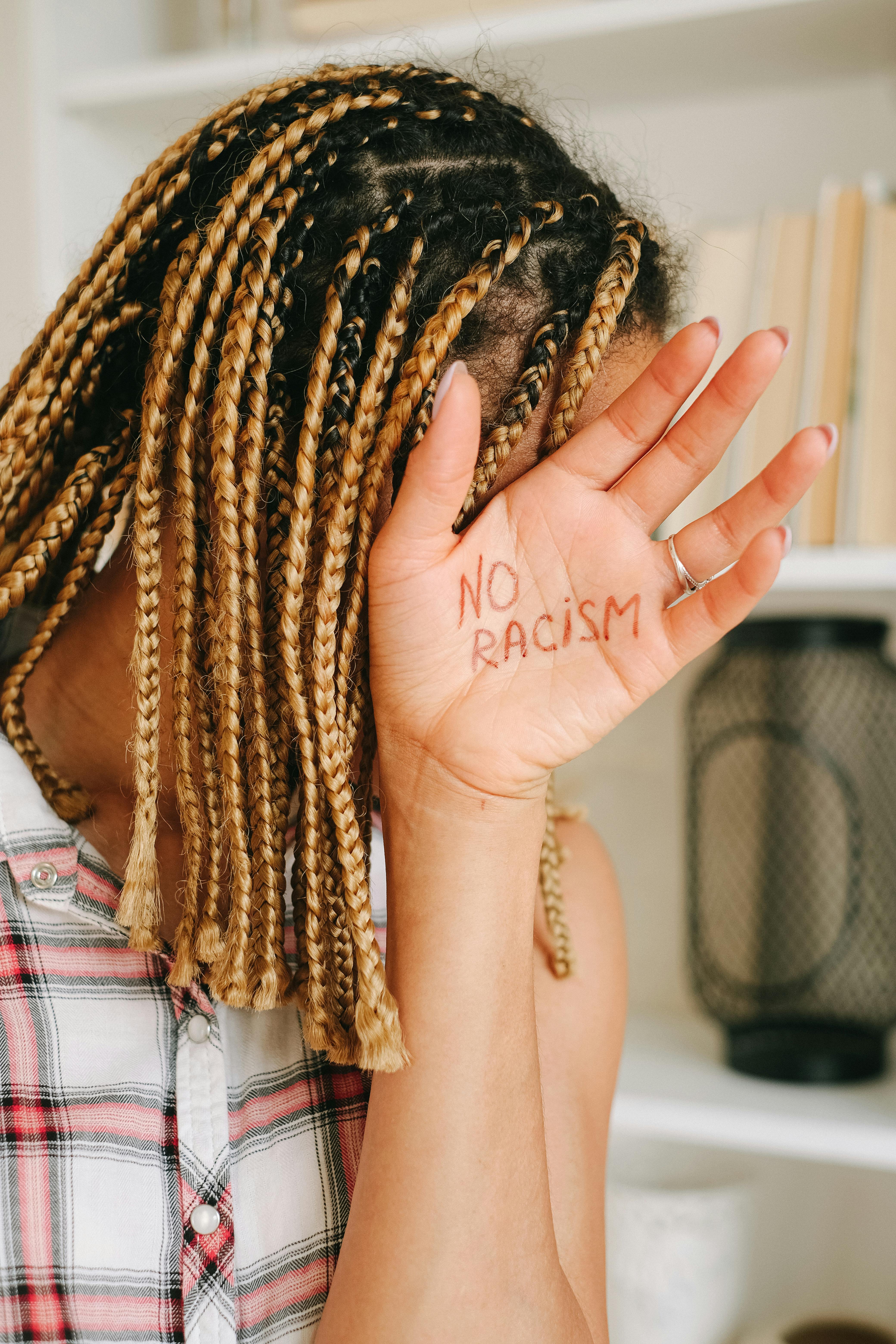 woman in white and pink plaid shirt covering her face with her hair