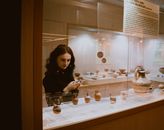 Woman examining vases in exhibition hall