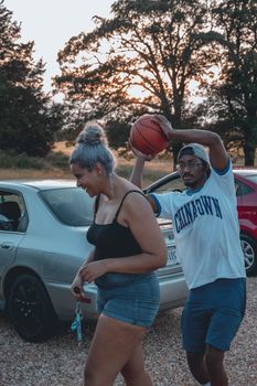 African American man flirting with plump teen girlfriend playing with basketball while spending time in nature