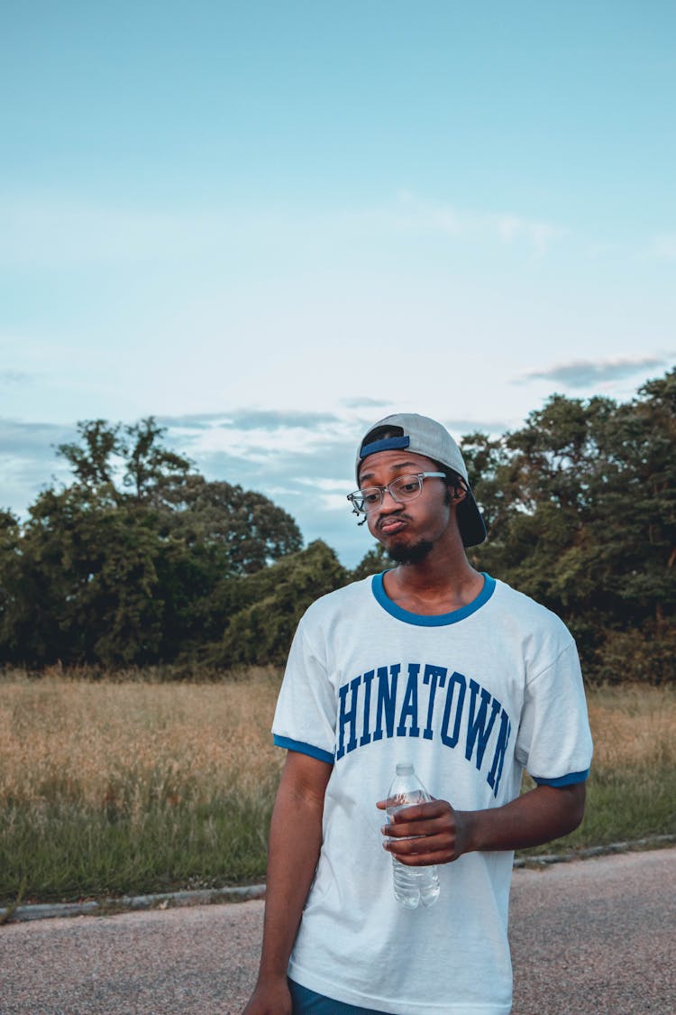 Black Man With Grimace And Bottle Of Water In Countryside