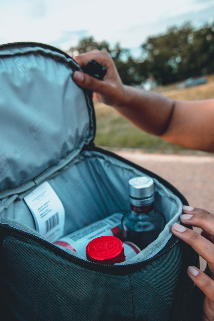 Person Opening Backpack With Small Bottles Inside