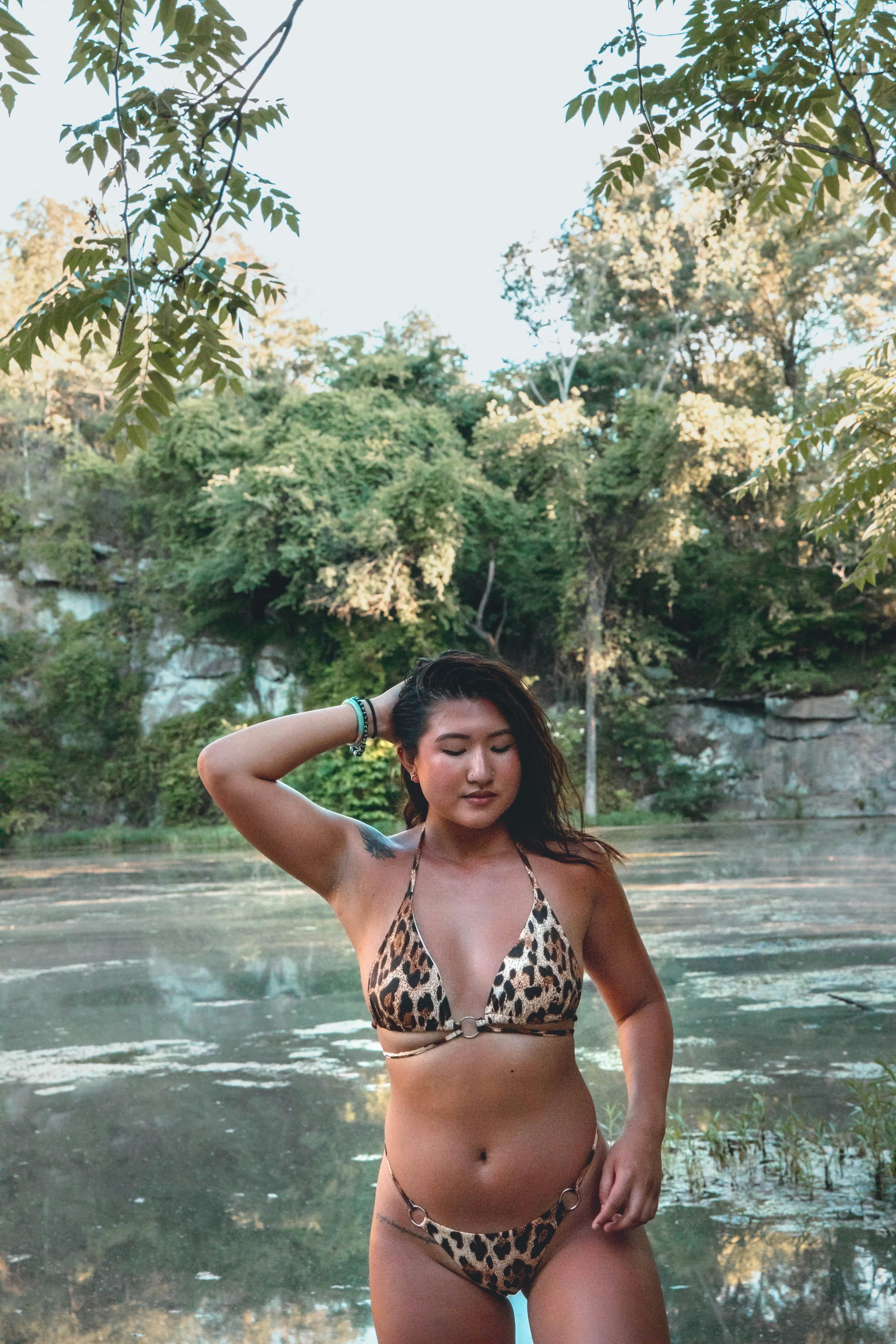 Sensual Asian woman in swimwear standing gracefully on lake shore ...