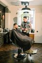 Man in Black and White Plaid Button Up Shirt Sitting on Black Barber Chair