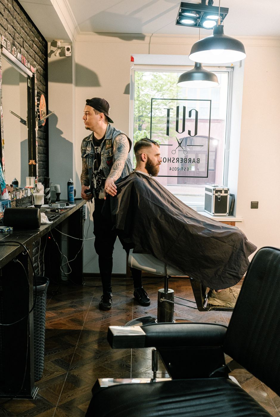 A barber working on a client in a stylish indoor barbershop setting