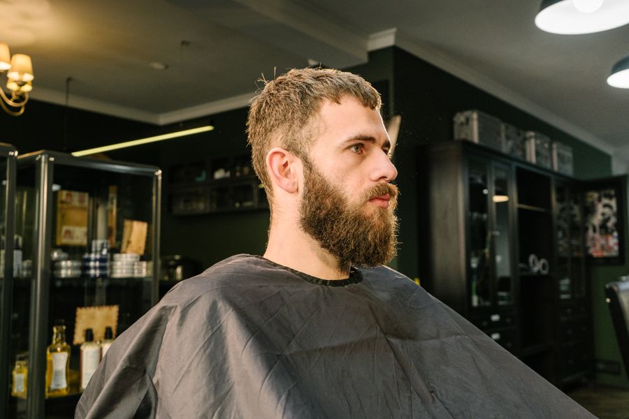 A barber in a dark cape mid-cut, seen in profile