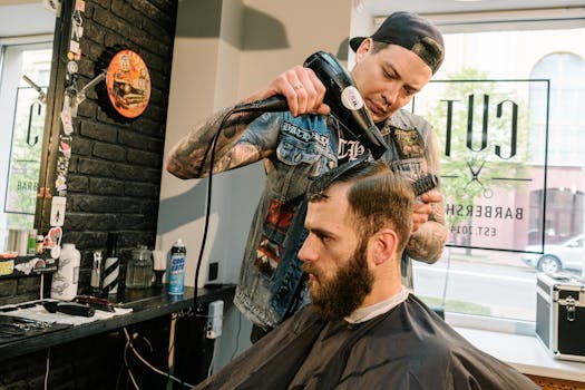 A barber uses a blow dryer to style a client's hair in a trendy barbershop setting.