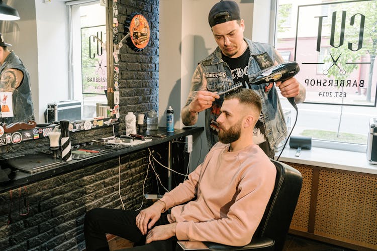 A Man In The Barbershop Sitting On A Black Barber Chair