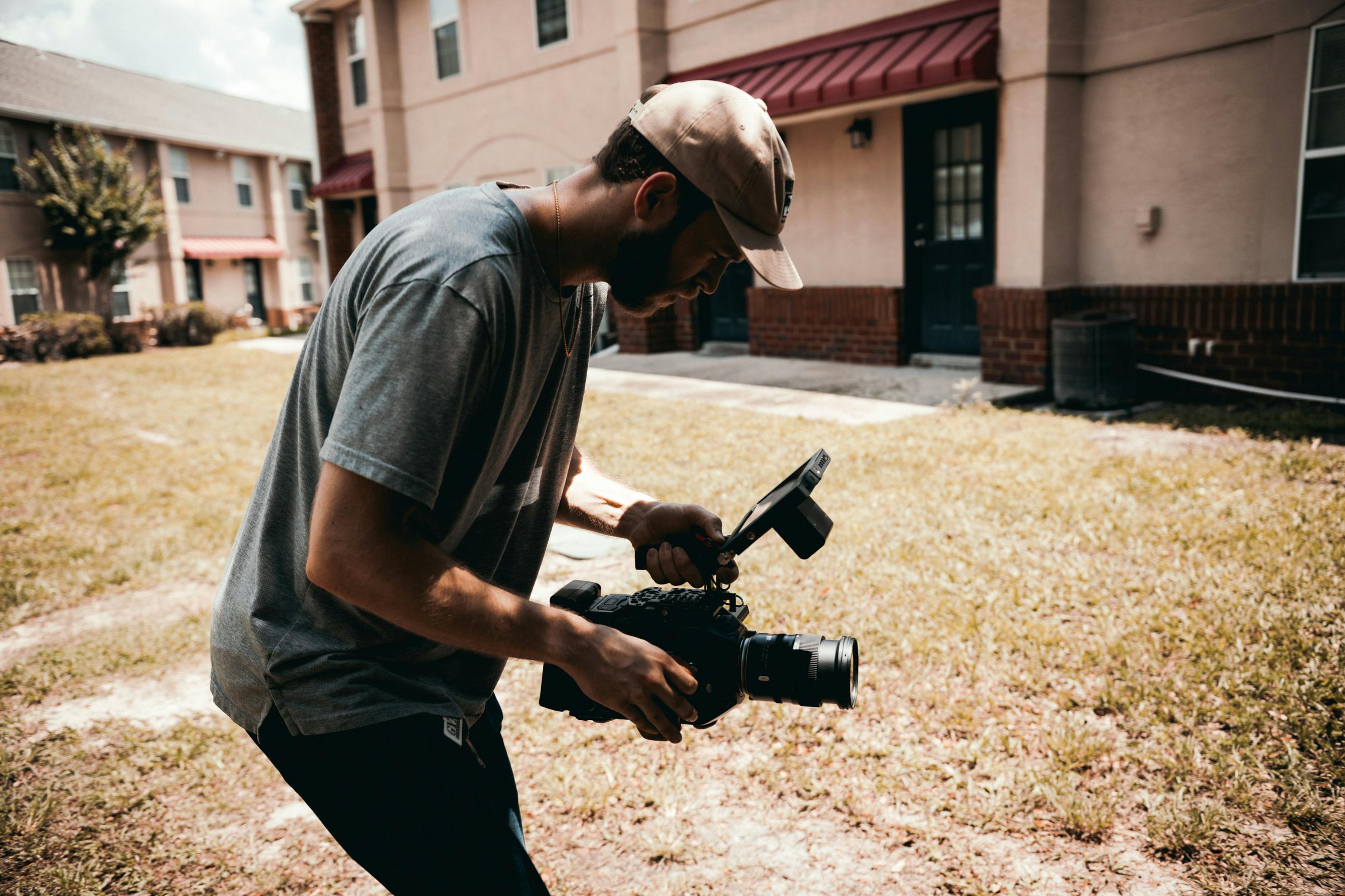 man in gray t shirt and black pants holding black dslr camera