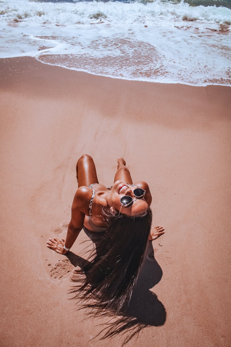 Fit Woman Sunbathing On Sandy Beach