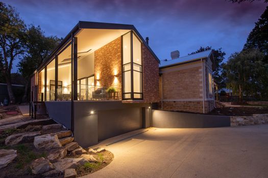 Contemporary residential cottage exterior with shiny lamps near walkway under sky in twilight