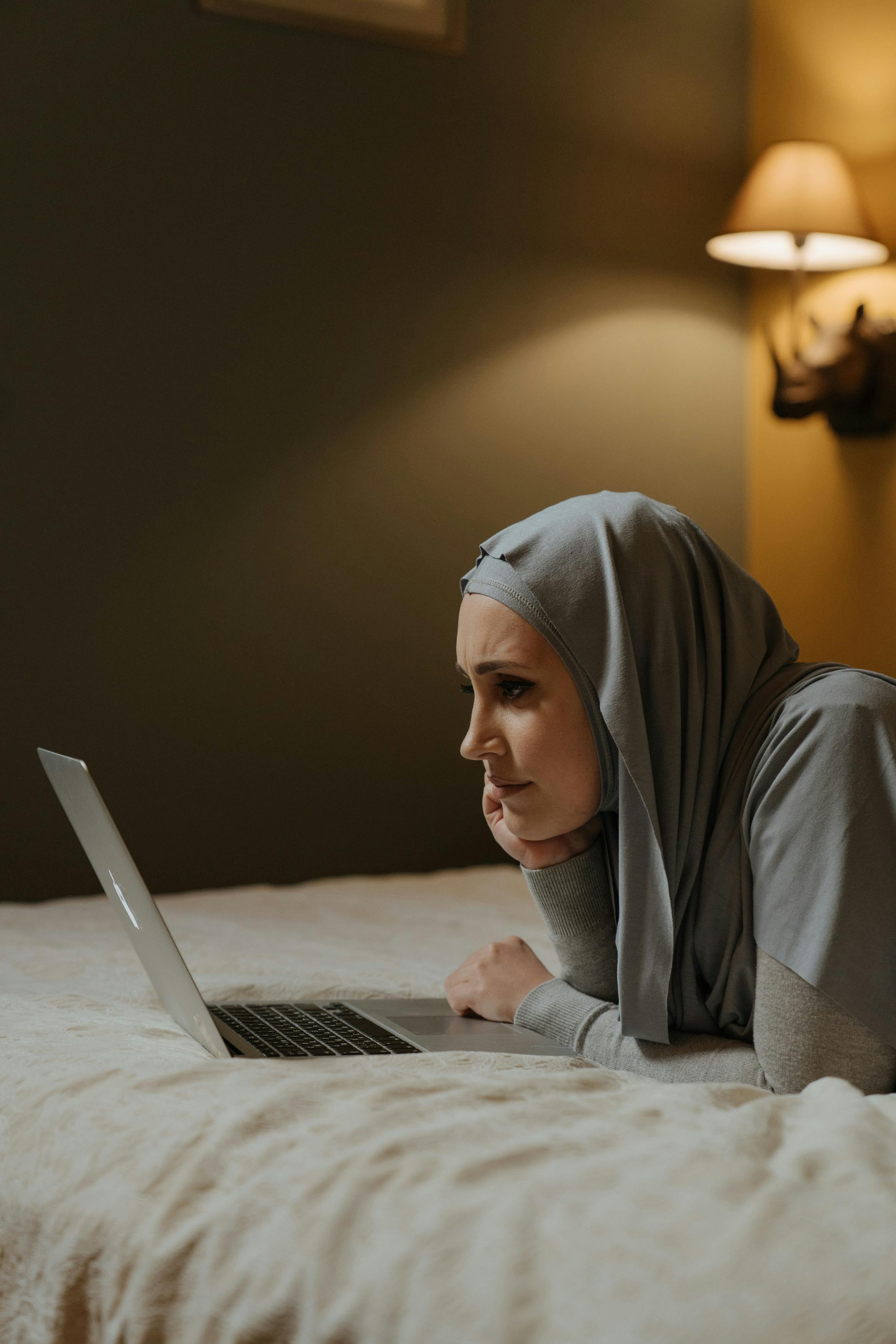 woman in gray hijab using macbook air