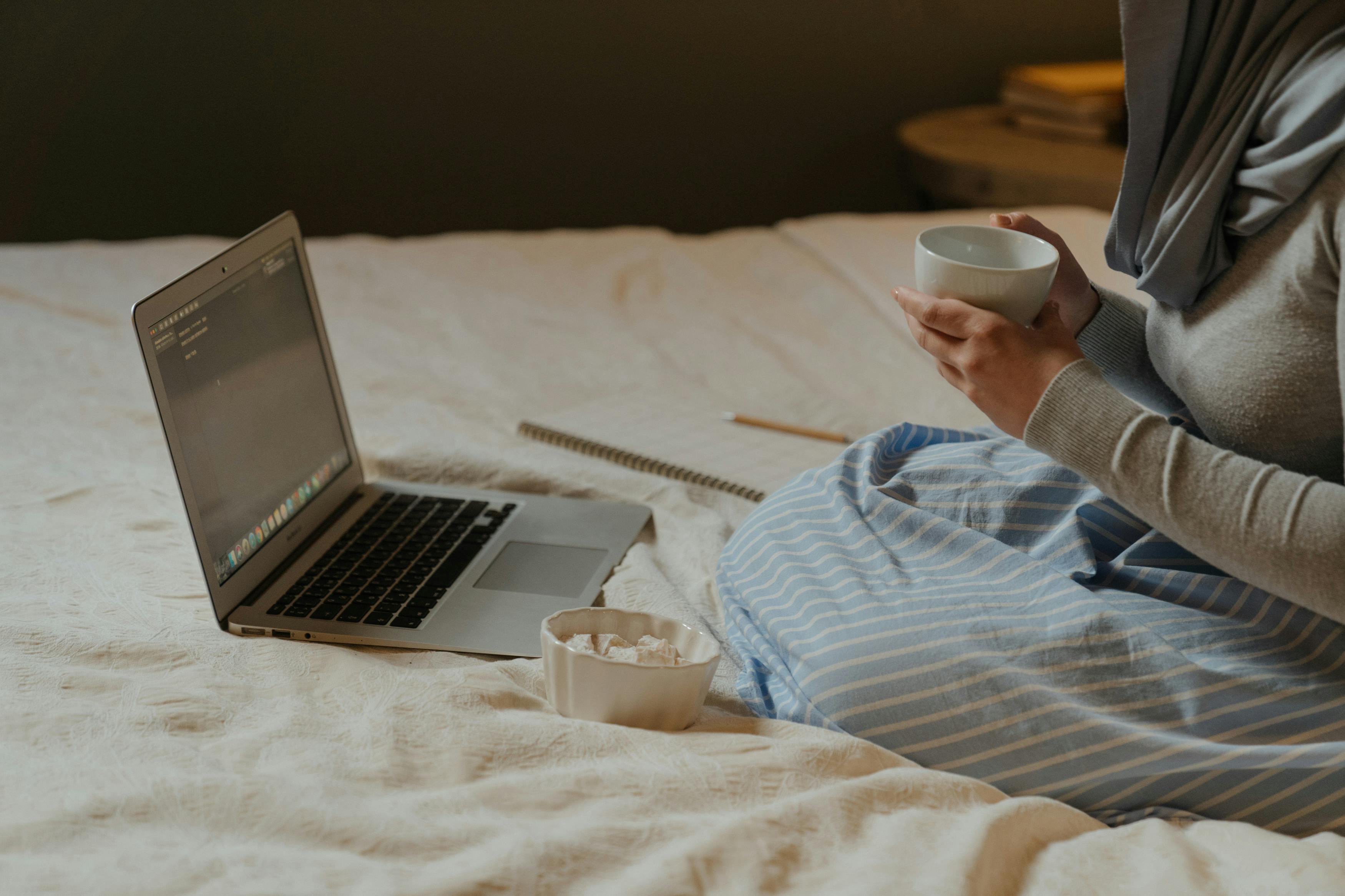 woman in white and blue striped dress shirt using laptop