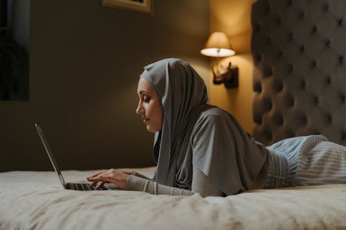 Free Woman in Gray Hijab Sitting on Bed Stock Photo