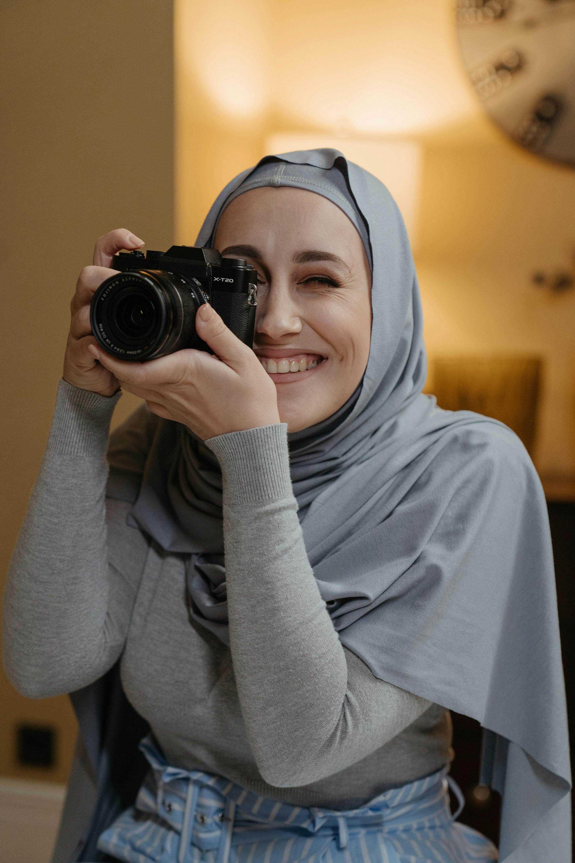 woman in gray hijab holding black camera