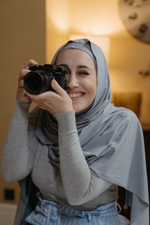 Free A woman in a hijab smiles while taking a photo indoors, showcasing diversity and joy. Stock Photo