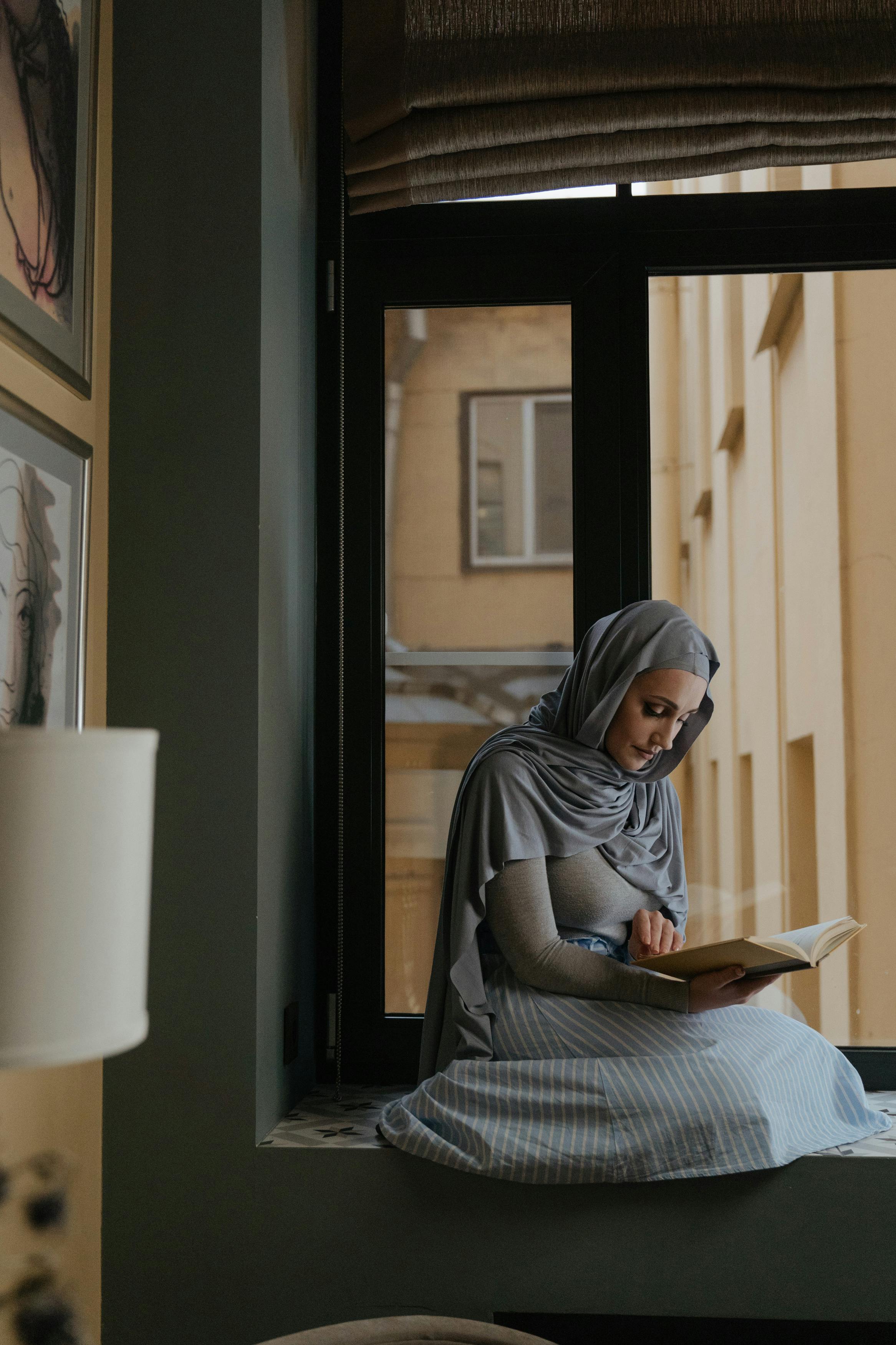 woman in gray hijab reading book