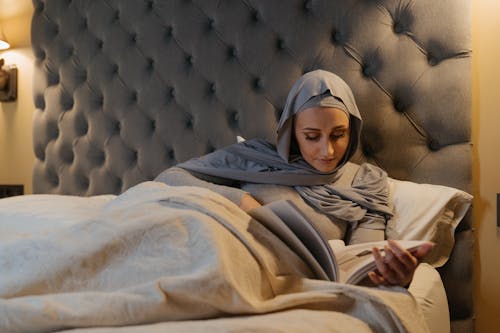 Woman in Brown Hijab Sitting on White Textile