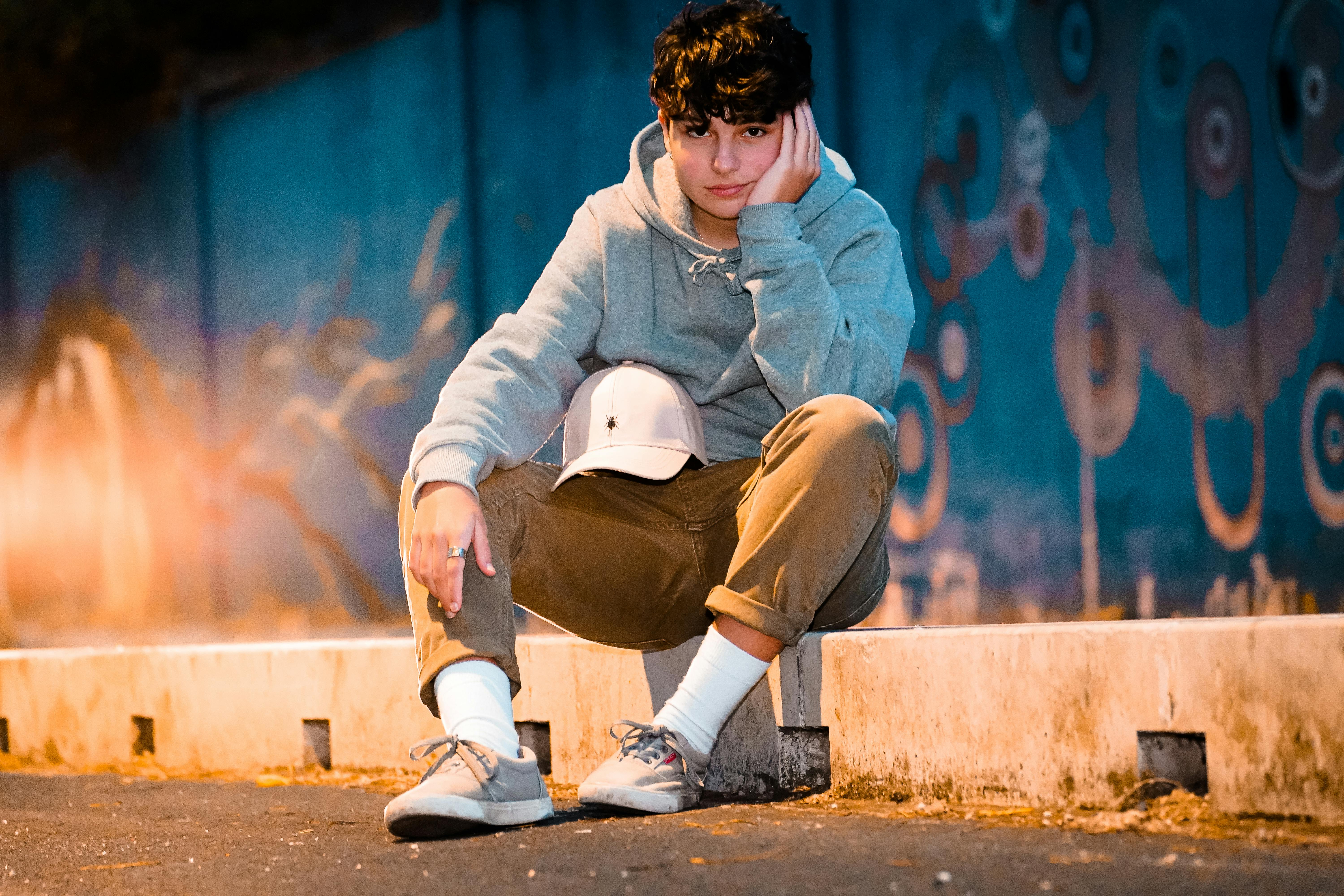 crop teen in modern apparel resting on barrier near road