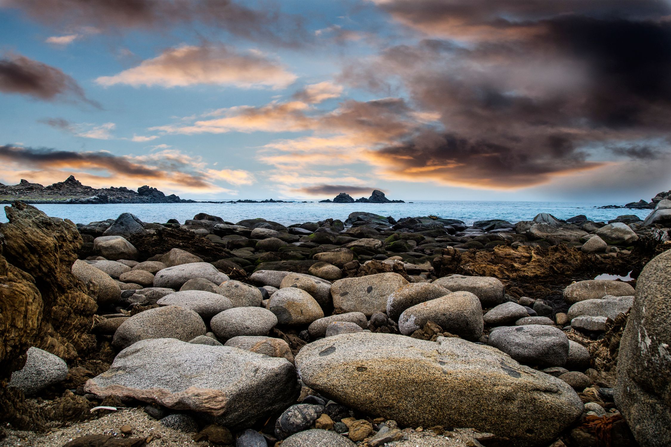 Rocky Seashore Under Black Clouds · Free Stock Photo