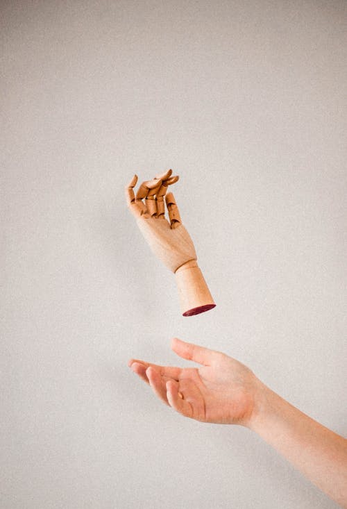 Person's Hand Catching a Wooden Hand 