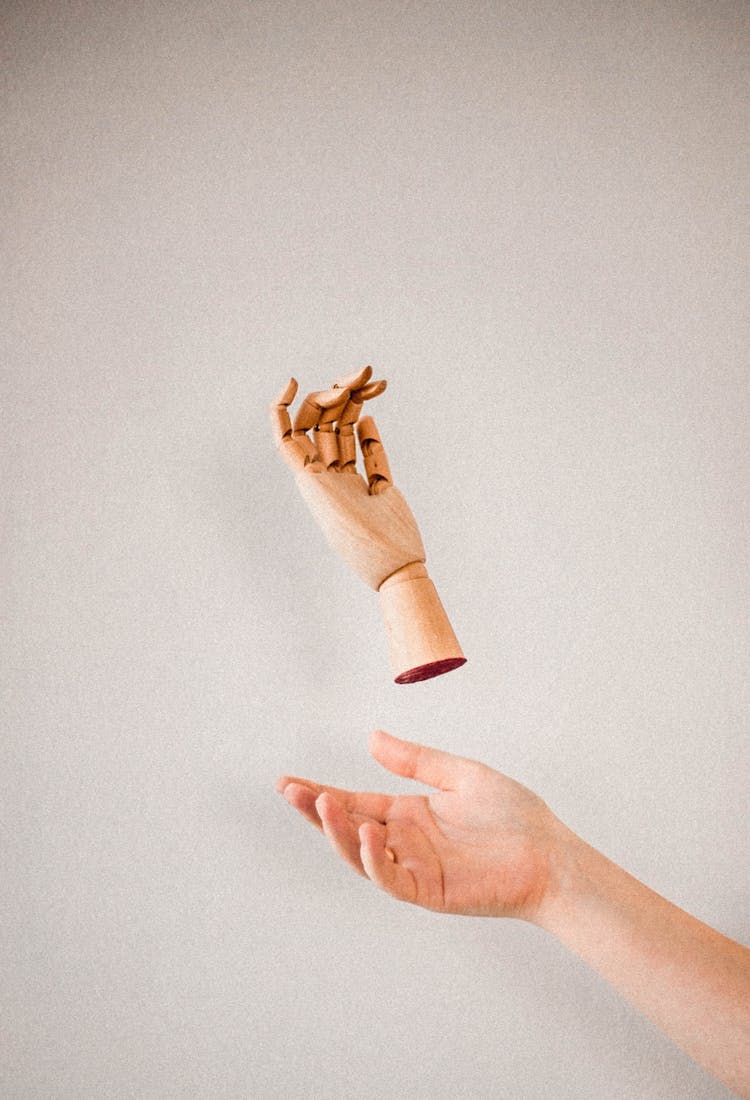 Person's Hand Catching A Wooden Hand 