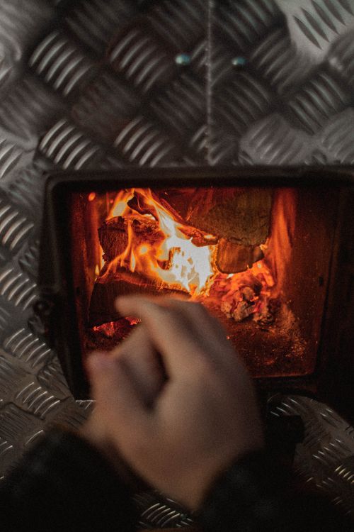 Free A warm, inviting indoor fireplace with vibrant flames and a person tending the fire. Stock Photo