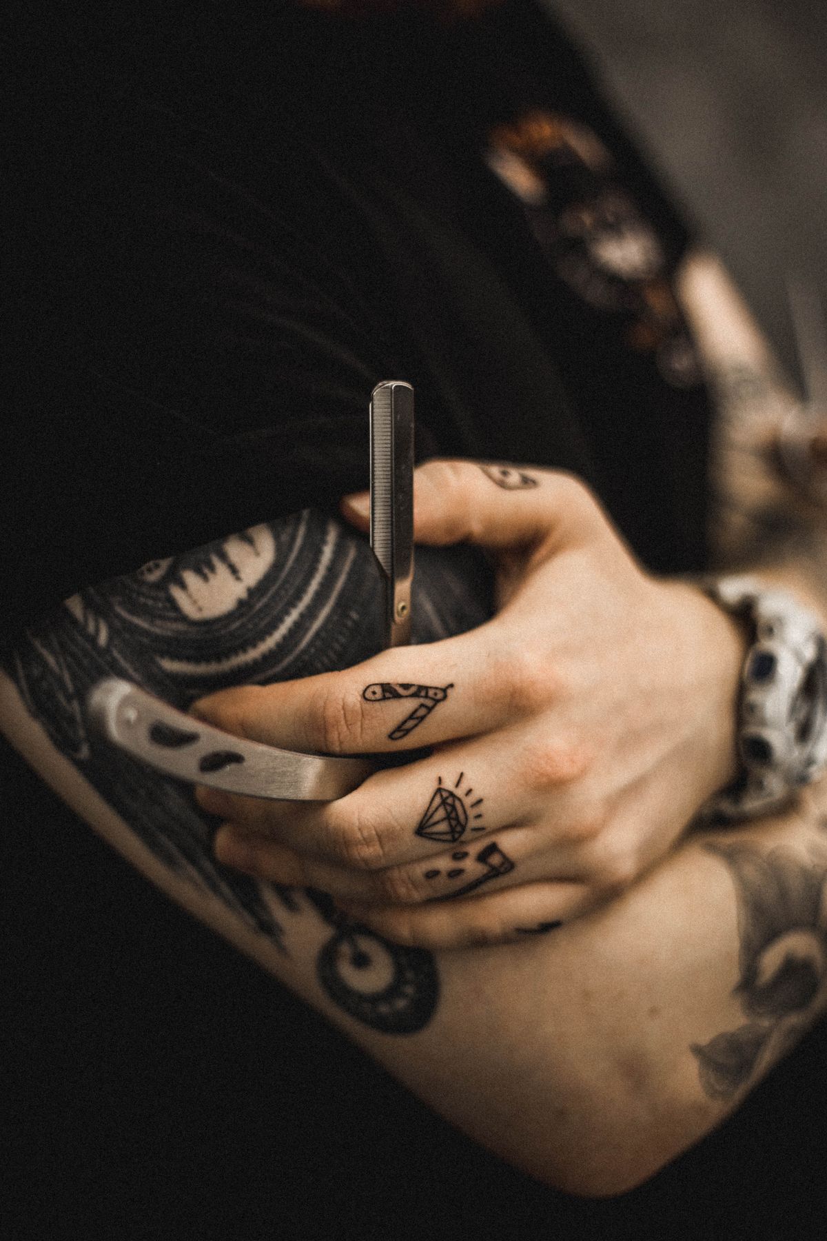Tattoo artist holding a machine, arms covered