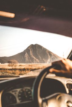 A scenic view of a mountain through a car window, depicting a journey and travel theme.