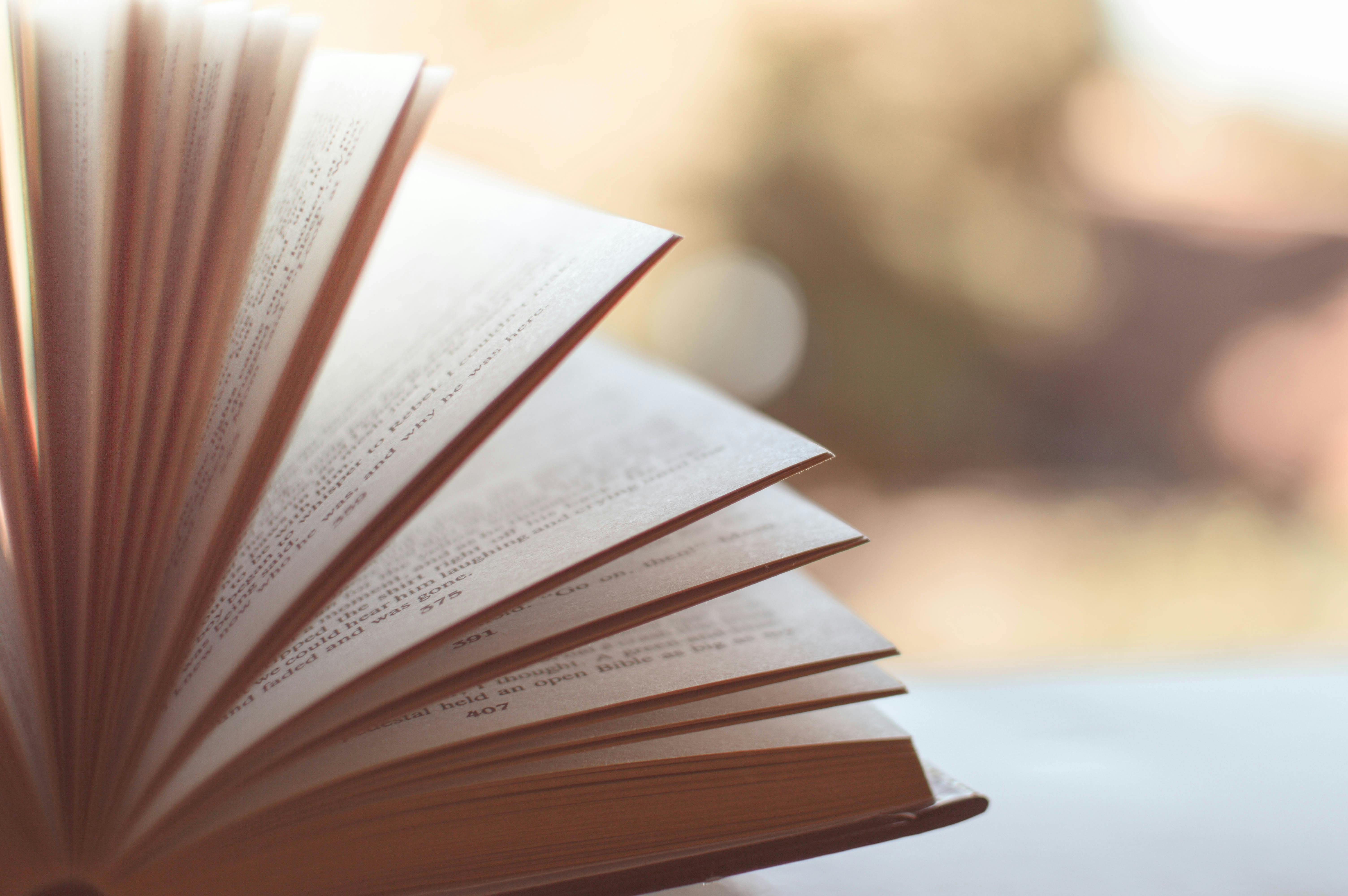 Book Opened on White Surface Selective Focus Photography · Free Stock Photo